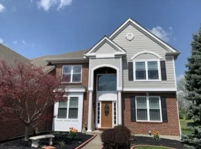 Restored two-story brick colonial home with fresh landscaping, arched entry and manicured beds in Batavia, Ohio by Abrams Restoration